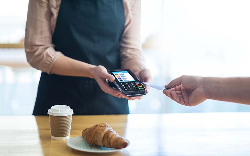 Woman holding wireless terminal while accepting a credit card payment. 
