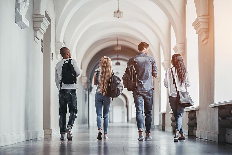Four students talking down the hall of a historic university. 