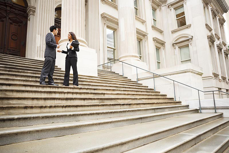 Man and woman having discussion on the steps of a government building. 