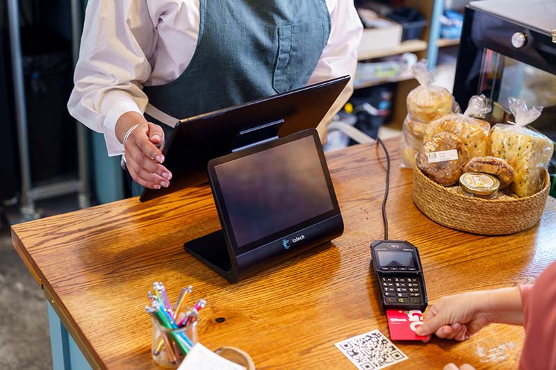 Woman paying for bakery purchase using talech Register. 